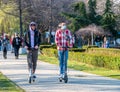 Two men riding electric scooters in King Mihai I park Herestrau, in Bucharest