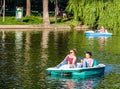 Bucharest, Romania - 2019. Young friends talking while pedal boating on the lake. Cheerful friends relaxing on pedal boat on hot Royalty Free Stock Photo