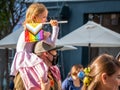 Young girl on the back of her father holding The rainbow flag, symbol of LGBT and queer pride at