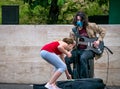 Bucharest/Romania - 05.23.2020 Young man with long hair playing guitar. Girl giving money to a street artist performing Royalty Free Stock Photo