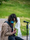 Bucharest/Romania - 05.23.2020 Young man with long hair playing guitar. Street artist performing Royalty Free Stock Photo