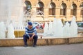 Bucharest, Rumania - 28.04.2018: Homeless man seating on fountain in Old Town Bucharest