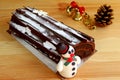 Buche de Noel Cake on Wooden Table with Blurry Dry Pine Cone and X`mas Ornaments in Background Royalty Free Stock Photo