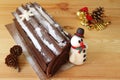 Buche de Noel or Chocolate Yule Log Cake with a Cute Snowman Marzipan and Dry Pine Cones, Christmas Ornament on Wooden Table Royalty Free Stock Photo