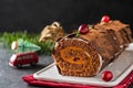 Buche de Noel. Traditional Christmas dessert, Christmas yule log cake with chocolate cream, cranberry. On stone gray background Royalty Free Stock Photo