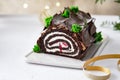 Buche de Noel. Traditional Christmas dessert, Christmas yule log cake with chocolate cream. Christmas tree branches. Royalty Free Stock Photo
