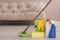 Bucket, cleaning supplies and mop on floor in living room, space for text Royalty Free Stock Photo