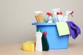 Bucket with cleaning supplies on table against grey background. Royalty Free Stock Photo