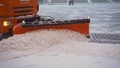 A bucket close-up cleans the sidewalk from snow. The tractor cleans the pavement in winter. Tractor cleaning the road from the Royalty Free Stock Photo