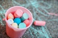 A bucket of colourful chalks against pavement full of scribbles. Toddler or child activity. Back to school.