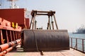 Bucket and crane for loading on cargo ship. Shipment from a merchant ship to a small ship. Grapple crane fill