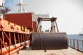 Bucket and crane for loading on cargo ship. Shipment from a merchant ship to a small ship. Royalty Free Stock Photo