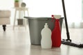 Bucket, different cleaning supplies and mop on floor indoors