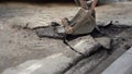 The bucket of the excavator breaks the old asphalt. Road repair work. Construction personnel