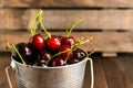 A bucket full of cherry over wooden background