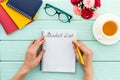 Bucket list. Blank notebook to write goals and wishes - with women hands - on green wooden office desk top-down mockup Royalty Free Stock Photo