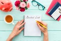 Bucket list. Blank notebook to write goals and wishes - with women hands - on green wooden office desk top-down mockup Royalty Free Stock Photo