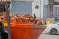 The bucket of a mini loader, which carries a fully loaded red brick down the street. An example of solving problems with low costs Royalty Free Stock Photo