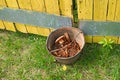 Bucket with old rusty hardware in the grass at the yellow fence