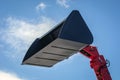 Bucket of a telescopic loader in black, against the sky