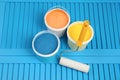 Buckets of paints and roller on light blue wooden background, above view Royalty Free Stock Photo