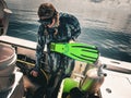 Woman scuba diver in dive skin dons green fins on boat at Buckeye Reef, Steinhatchee, Florida