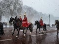 Buckingham palace hyde park guard change winter snowing snowflakes riding on horses red uniform jacket helmet London uk