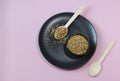 Buckwheat grains on black plate and buckwheat in a bowl, pink background. Gluten free grain for healthy diet. Top view Royalty Free Stock Photo