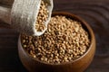 Buckwheat groats hulled seeds in bowl and burlap bag on wooden table