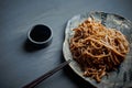 Buckwheat noodle with teriaki sauce.Asian dish. With wooden sticks. On a clay plate and a gray background. Royalty Free Stock Photo