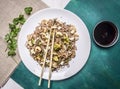 Buckwheat noodles with squid and seafood on a white plate with chopsticks, soy sauce wooden rustic background top view Royalty Free Stock Photo