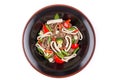 Buckwheat noodles with squid and vegetables with teriyaki sauce isolated on a white background. Buckwheat noodles in a black plate