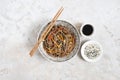 Buckwheat noodles with vegetables and meat decorated with sesame and seaweeds in bowl on grey background. Top view Royalty Free Stock Photo