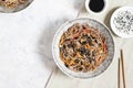 Buckwheat noodles with vegetables and meat decorated with sesame and seaweeds in bowls on grey background Royalty Free Stock Photo