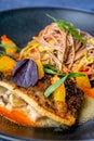 Buckwheat noodles on wok and baked carp. Asian cuisine. The work of a professional chef. Dish from a restaurant or cafe menu.
