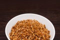 Buckwheat porridge with butter in a small white plate. Buckwheat porridge on a brown background. Bowl with boiled