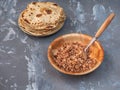 Buckwheat porridge in a deep plate with a slice of butter and a stack of freshly baked tortillas on a gray background Royalty Free Stock Photo