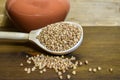 Buckwheat in a wooden spoon, next to a clay pot on a brown wooden background. Royalty Free Stock Photo