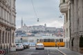 Buda Castle seen from Pest with a tram and a car passing in front. The castle is historical palace complex of the Hungarian kings