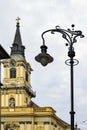 Budapest cityscape: view of the tower of the Catholic Church with cross and an old street lamp on street of city against cloudy