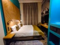 Nicely decorated hotel room with twin bed, small table and wardrobe with safe