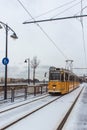 BUDAPEST, HUNGARY - DECEMBER 02, 2019: Yellow tram and tramlines in Budapest at winter with snow near the embankment on Royalty Free Stock Photo