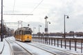 BUDAPEST, HUNGARY - DECEMBER 02, 2019: Yellow tram and tramlines in Budapest at winter with snow near the embankment on Royalty Free Stock Photo