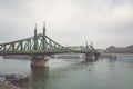 Budapest, Hungary - Nov 6, 2019: Liberty Bridge over the Danube river on a foggy rainy autumn day. Cruise ship and historical Royalty Free Stock Photo