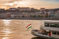 Budapest, Hungary - Nov 6, 2019: Part of tourist boat with waving Hungarian flag in the sunset light. Historical center in the