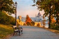 Budapest, Hungary - Bench at Varkert Bazaar with lamp post, autumn foliage, Szechenyi Chain Bridge and Parliament at background