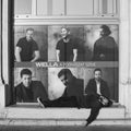 BUDAPEST, HUNGARY - SEPTEMBER 17, 2016: Homeless looking man sleeping on window ledge in front of photos of successful looking men