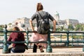 Two young caucasian women sitting and leaning against a steel railing by the Danube river in Budapest Hungary.