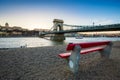 Budapest, Hungary - Traditional red bench at the riverside with Szechenyi Chain Bridge, Buda Castle Royal Palace Royalty Free Stock Photo