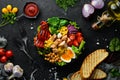 Buddha Bowl: Chicken, chickpeas, broccoli, tomatoes, egg, paprika, onion in a black plate on a black background.